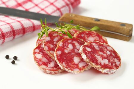 thin slices of dry cured sausage and knifeの写真素材