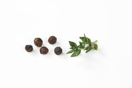black peppercorns and fresh thyme on white backgroundの写真素材