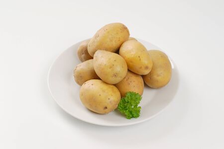 raw unpeeled potatoes on plateの写真素材