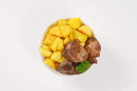 bowl of pan fried potatoes and chicken liver on white backgroundの写真素材