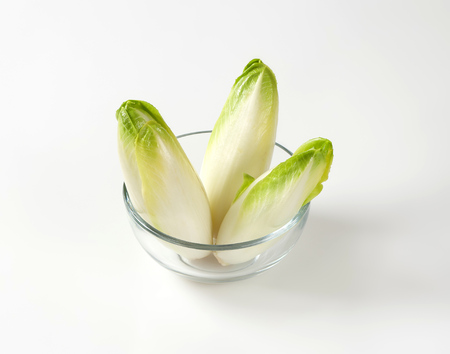 three fresh Belgian endive heads (Witloof chicory) in glass bowlの写真素材