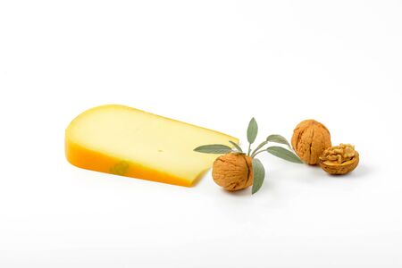slice of gouda cheese with walnuts and sprig of sage on white backgroundの写真素材