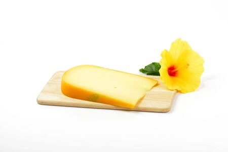 slice of gouda cheese with hibiscus flower on wooden cutting boardの写真素材