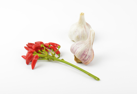 Bunch of small red chili peppers and garlic bulbs on white backgroundの写真素材