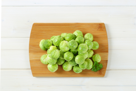 heap of raw Brussels sprouts on wooden cutting boardの写真素材