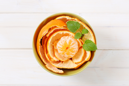peeled tangerine arranged in peels in green bowlの写真素材