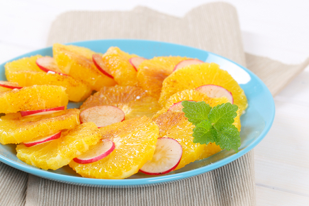 slices of orange and radish sprinkled with cinnamon on turquoise plateの写真素材