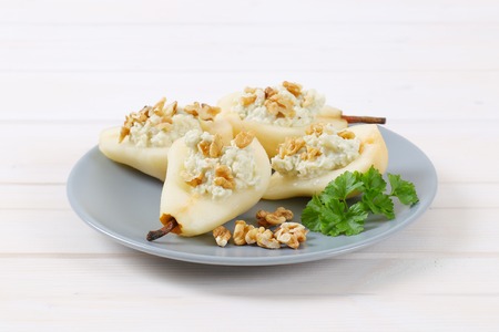 plate of halved pears with blue cheese and walnuts on white backgroundの写真素材