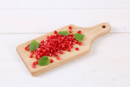 pile of pomegranate seeds on wooden cutting boardの写真素材