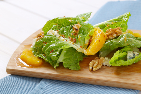 Chinese cabbage salad with orange, walnuts and blue cheese on wooden cutting boardの写真素材