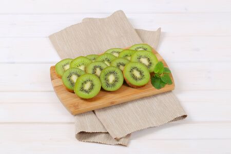 slices of ripe kiwi arranged on wooden cutting boardの写真素材
