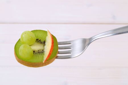slice of kiwi with grapes and apple on forkの写真素材