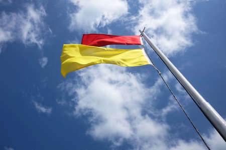 red and yellow safe bathing area flag against sky