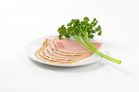 slices of asparagus coated ham with parsley on white plateの写真素材