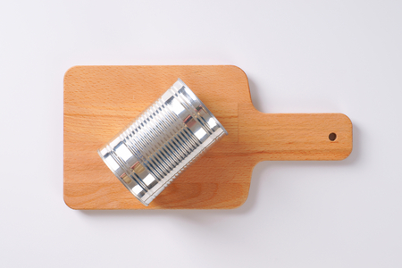 closed silver can on wooden cutting boardの写真素材