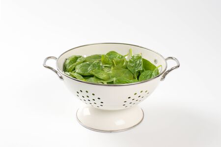 fresh spinach leaves in white colanderの写真素材