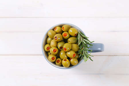 cup of green olives stuffed with red pepper on white backgroundの写真素材