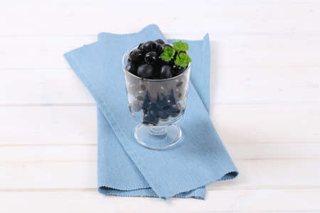 glass of black olives with fresh parsley on blue place matの写真素材