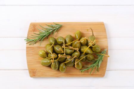 pile of pickled caper berries on wooden cutting boardの写真素材