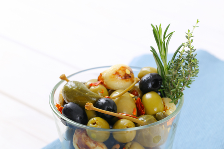 glass of pickled olives, capers, caper berries and garlicの写真素材