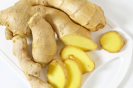 Fresh ginger root on white plastic cutting board