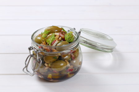 jar of marinated green olives on white wooden backgroundの写真素材