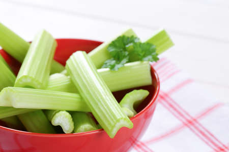 bowl of green celery stems on checkered dishtowel - close upの写真素材