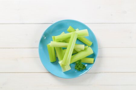 plate of green celery stems on white wooden backgroundの写真素材