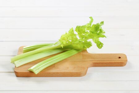 stems of green celery on wooden cutting boardの写真素材