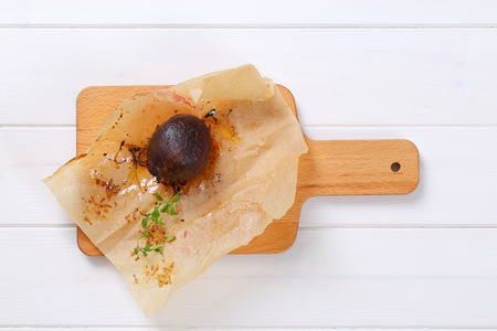 baked whole beet with olive oil and thyme on wooden cutting boardの写真素材