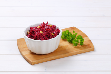 bowl of fresh beetroot spread with walnuts on wooden cutting boardの写真素材