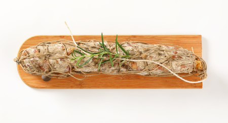 Dry cured pork sausage and rosemary on wooden boardの写真素材