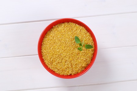 bowl of dry wheat bulgur on white wooden backgroundの写真素材