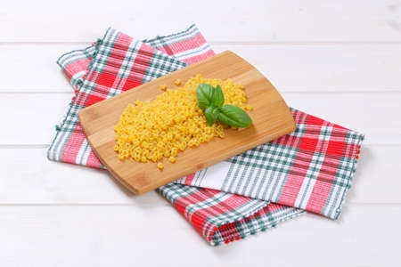 pile of small pasta shells on wooden cutting board