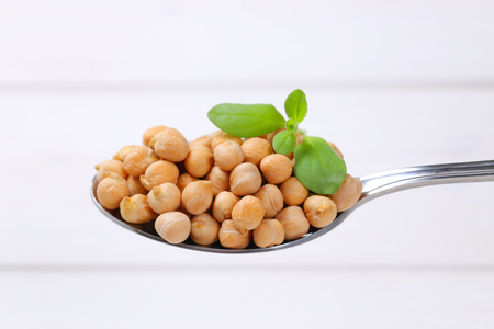 spoon of raw chickpeas on white wooden backgroundの写真素材