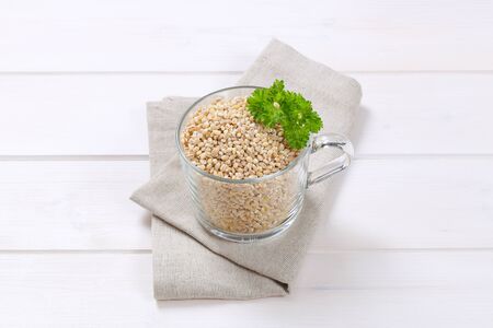 cup of pearl barley on on beige place matの写真素材