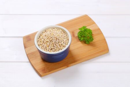 bowl of pearl barley on wooden cutting boardの写真素材