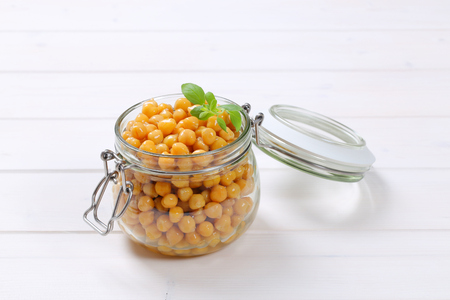 jar of cooked chickpeas on white wooden backgroundの写真素材