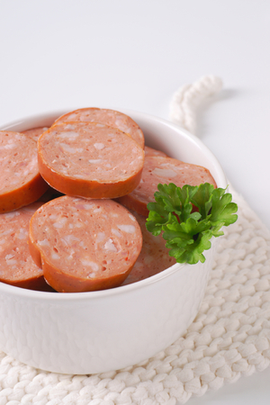 bowl of sliced pork sausage on white table matの写真素材