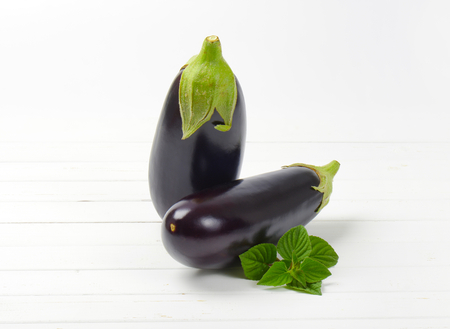 two fresh eggplants and sage on white wooden backgroundの写真素材