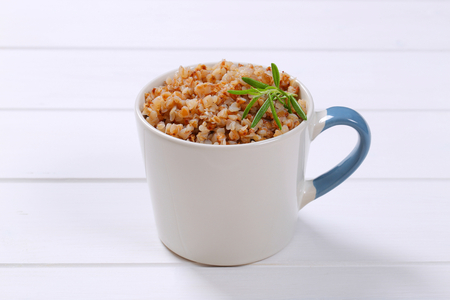 mug of cooked buckwheat on white wooden backgroundの写真素材