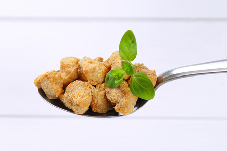 spoon of soy meat cubes on white wooden backgroundの写真素材