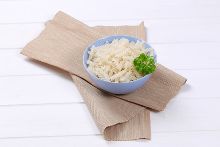 bowl of cooked rice pasta fusilli on beige place matの写真素材