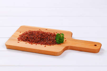 pile of red rice on wooden cutting boardの写真素材