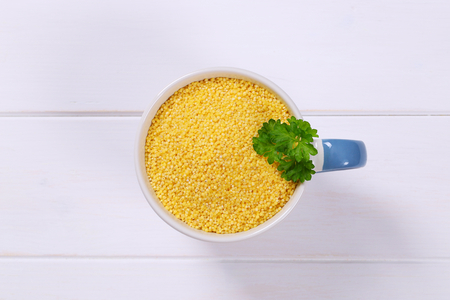 mug of raw millet on white wooden backgroundの写真素材