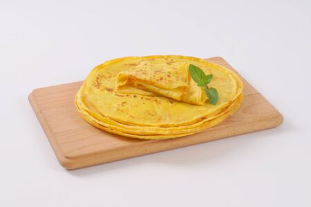 stack of freshly fried pancakes on wooden cutting board