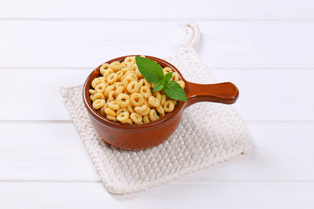 saucepan of honey cereal rings on white table  matの写真素材