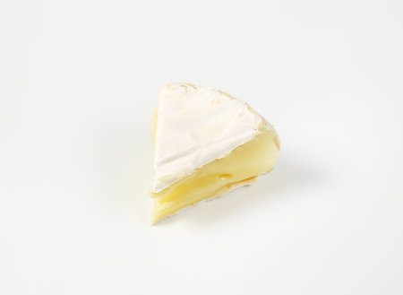 piece of soft-ripened cheese with white rindの写真素材