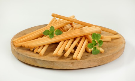 crispy bread sticks on round wooden cutting board