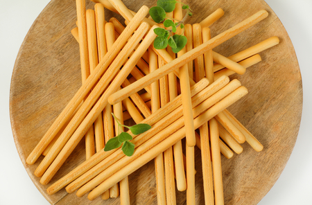 crispy bread sticks on round wooden cutting board - close up